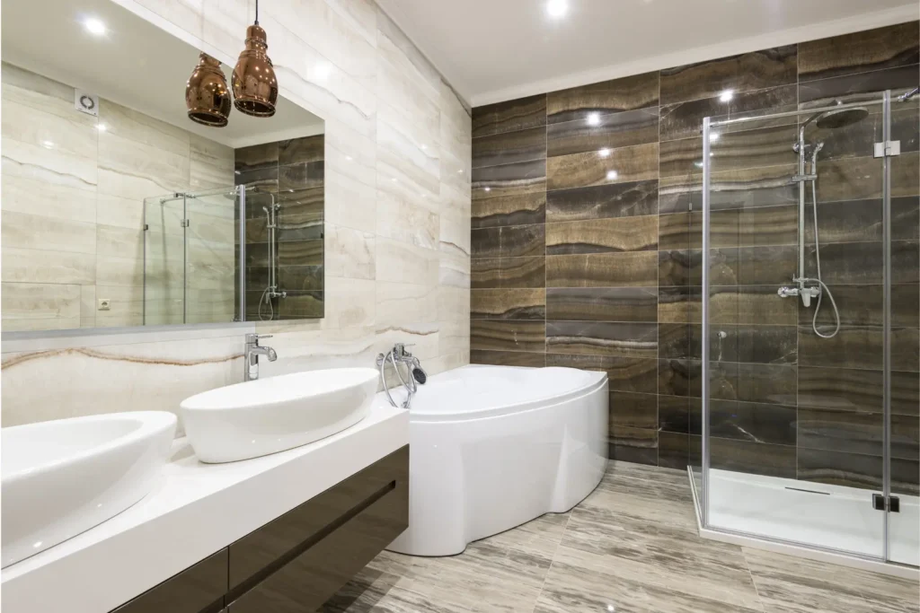 Professional real estate announcement showing a contemporary design bath with double sink, corner bathtub, glass shower and walls covered in wood and marble tones. A space that combines elegance and comfort in housing.